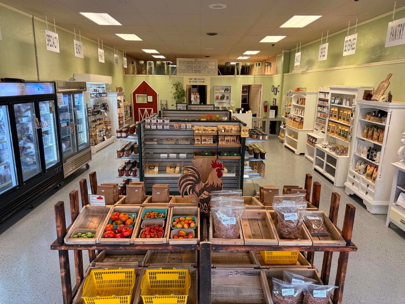 Inside Sunny Creek Trading Post — produce crates, the wooden rooster, and shelves of local goods from Kay County producers