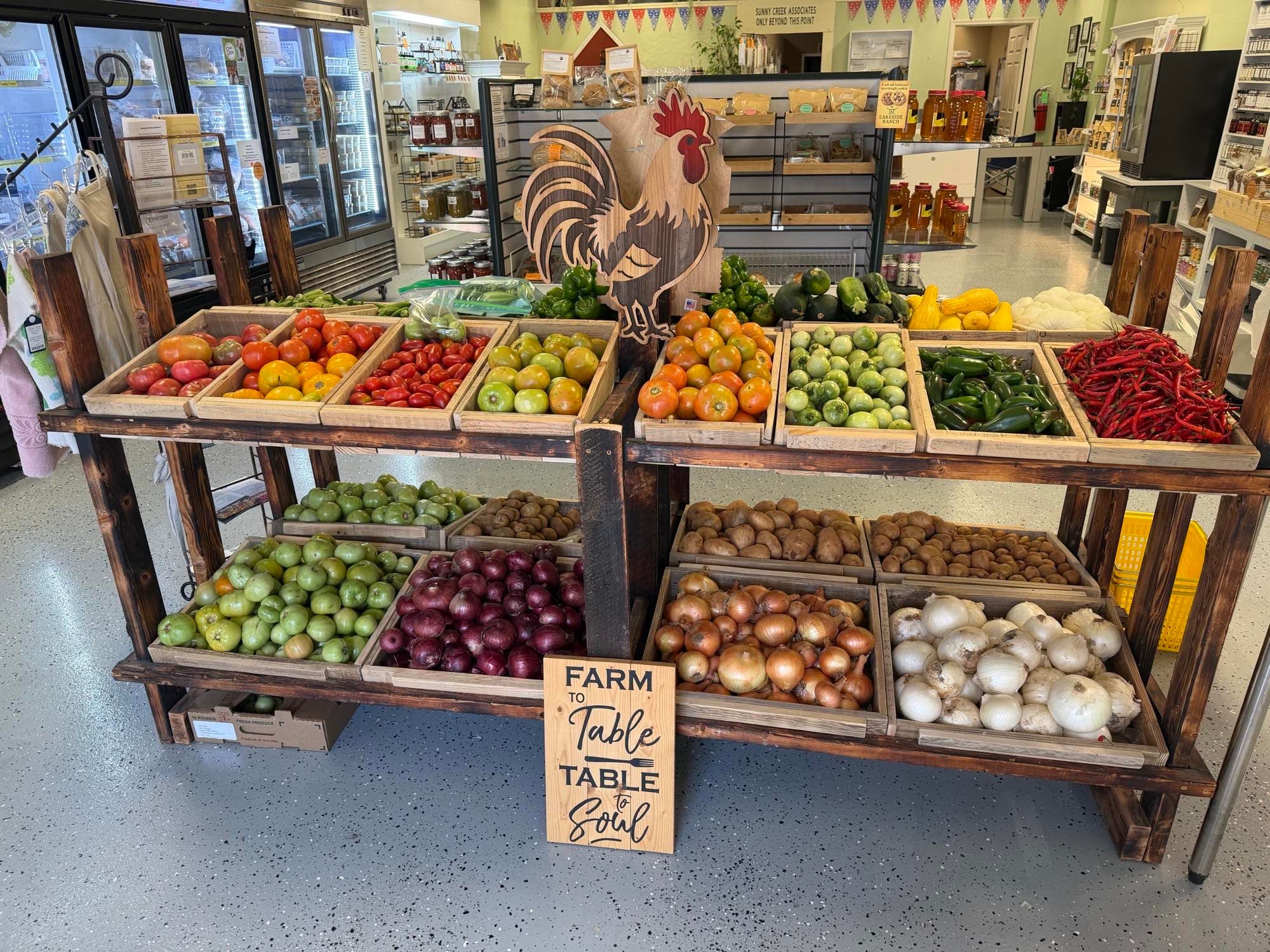Inside Sunny Creek Trading Post — produce crates, the wooden rooster, and shelves of local goods from Kay County producers